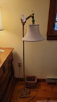 Full view of vintage floor lamp standing next to a wooden dresser, showing the lamp's height and base details.