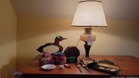 Front view showing lamp, duck mirror, trinket box, mixed nuts tin, ceramic dish, wooden box, travel clock, and assorted watches on table