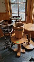 Photo showing two dark wood fern stands with twisted legs and two round wooden pedestal tables with octagonal wood planter on one table.