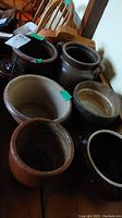 Top view of multiple pottery pots showing variation in size, rim color, presence of handles, and different earthy tones.