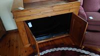 Vintage pine cabinet with both doors open revealing inside space for storage or TV components.