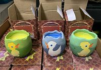 Photo showing three porcelain egg-shaped candles with duck designs and their boxes behind them