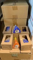 Photo showing sealed cardboard boxes stacked with multiple boxed candles and a couple unboxed candles visible on top.
