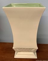 Front view of Red Wing square tapered vase with pale green interior and off-white exterior on wooden surface, showing textured band detail near the base.