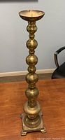 Full view of tall brass candlestick holder showing its rounded stacked design and shallow candle holder top.