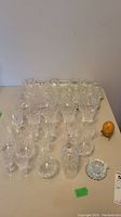 Crystal stemware including multiple brandy glasses and punch bowl glasses arranged on a table with a tray and small round dish.