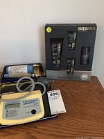 Photo showing LifeSource digital blood pressure monitor UA-702 with cuff and tubing alongside Nirvana Spa men's skincare kit in original packaging.