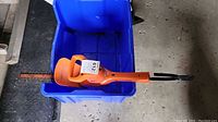 Photo of Black and Decker hedge trimmer inside a blue plastic bin from a side view showing the blade and handle.