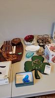Overview of assorted kitchenware including glassware, clock, wooden cheese board and small dishes on a table