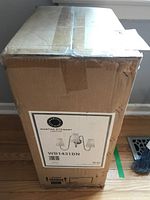 Cardboard box showing the Martha Stewart Lighting label with model number WB1431BN, indicating a three-arm wall light fixture as pictured on label.