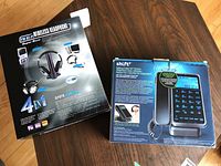 Front and back of the two boxes on a wooden surface, showing branding and features of Shift3 phone and SF878 wireless headphones.