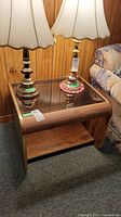 Side view of wooden end table with glass top and lamps on top.
