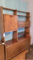 Full front view of cabinet showing shelving, drop-down bar door, drawers and lower sliding doors
