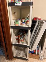 Photo of first plastic shelving unit with three shelves filled partially with canned food and other small items