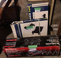 Photo showing three boxed items: MotoMaster hydraulic trolley jack with axle stands in a black box, and two boxes of 2-piece wheel dollies in blue and white packaging.