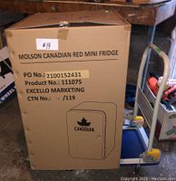 Sealed cardboard box labeled Molson Canadian red mini fridge showing PO No.: 2100152431, Product No.: 111075 and Excello Marketing
