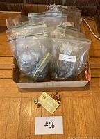 Full collection in cardboard box showing multiple labeled resealable bags containing different rock specimens along with a small group of vintage pins spread out in front of the box.