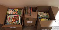 Three cardboard boxes filled with vintage children's books, including various colorful spines and covers visible.