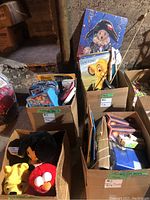 Boxes of toys and dolls in basement showing collection and labels.