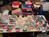 Wide overview of the arts and crafts supplies spread on a table, showing multiple packets of beads, wooden cutouts, and other materials.