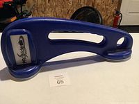 Blue ProSlide curling slide with handle grip and foot pads on ends on table.