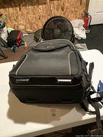 Side/top view of black Gator backpack showing zippered compartments, padded shoulder straps, and carrying handle on table.