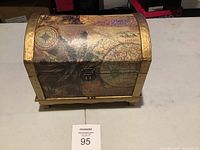 Photo showing front view of jewelry box with domed lid, vintage map and botanical print, gold trim, and center latch.