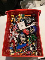 A red bin filled with assorted LEGO pieces and a transforming robot toy figure visible on top