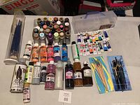 Lot contents from a distance showing paints, brushes and storage box on a table.