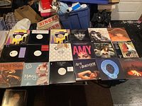 Full view of 18 vinyl records spread out on table including singles and albums by Mary J. Blige, Amy Winehouse, and others.
