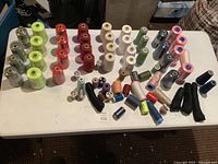 Full table view showing total lot with large and small spools of thread in various colors arranged on a table.