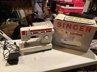 Singer electronic sewing machine model 9006 on a white table with the original box behind it.