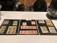 Three black stock sheets with multiple blocks and strips of vintage stamps including Canadian and other countries, arranged in rows.