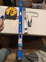 Full lot viewed on table showing all tools including spirit levels, extension reel, paint roller, and screwdriver.