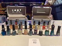 Photo shows 15 nail polish bottles in front of two silver carrying cases with mirror interiors, arranged in a row on a white surface.