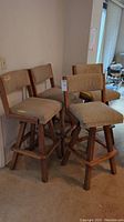 Four oak swivel bar stools grouped together showing overall condition and structure.