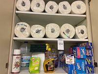 Full view of two shelves with paper towels on top shelf, various cleaning supplies and storage bags on second shelf.