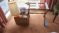 Photo shows wood luggage rack, orange lamp with beige shade, and box containing twin size quilted heated blanket and heating pad
