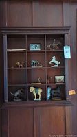 Front view of dark wood curio cabinet with various animal figurines arranged in compartments.