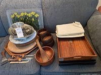 Full view of assorted trays and bowls on sofa, including wooden trays, bowls, marble trays, cheese knives/spreaders.