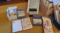 Seven plus file boxes and small containers filled with binders, glassine envelopes and loose stamps displayed on carpet