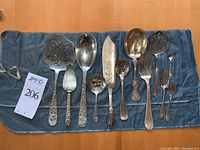Twelve sterling serving utensils laid on blue flannel roll