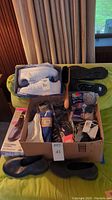 Full lot view showing Adidas white shoes in box, rubber overshoes, assorted socks in packaging, and wooden shoe brush.