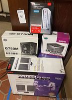 Photo of all boxed items: RCA wireless speakers, Motorola SURFboard eXtreme cable modem, Cooler Master G750M and Extreme Power Plus 600W power supplies