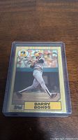 Front view of Barry Bonds rookie baseball card showing player batting in game, Topps branding visible.