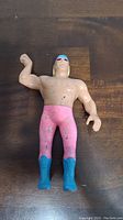 Front view of the Jesse Ventura wrestling action figure showing pink tights, blue boots, and blue headband with muscle detail and paint loss.