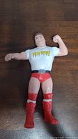 Front view of Rowdy Roddy Piper action figure wearing white Hot Rod T-shirt, red trunks and boots, with arms posed.