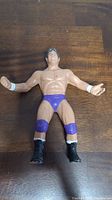 Front view of the Tito Santana figure showing molded black hair, purple trunks, black boots, and white wrist tape.