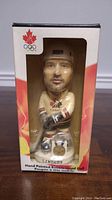 Eric Lindros bobble head in cream Team Canada hockey jersey holding hockey stick, in original box with visible maple leaf and Olympic rings logo.