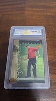 Front of the 1997 Upper Deck Tiger Woods rookie card showing Tiger Woods in a red shirt on course, encased in a protective WCG 10 graded slab.